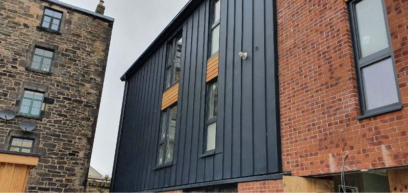 Building showing part fitting of new dark grey cladding